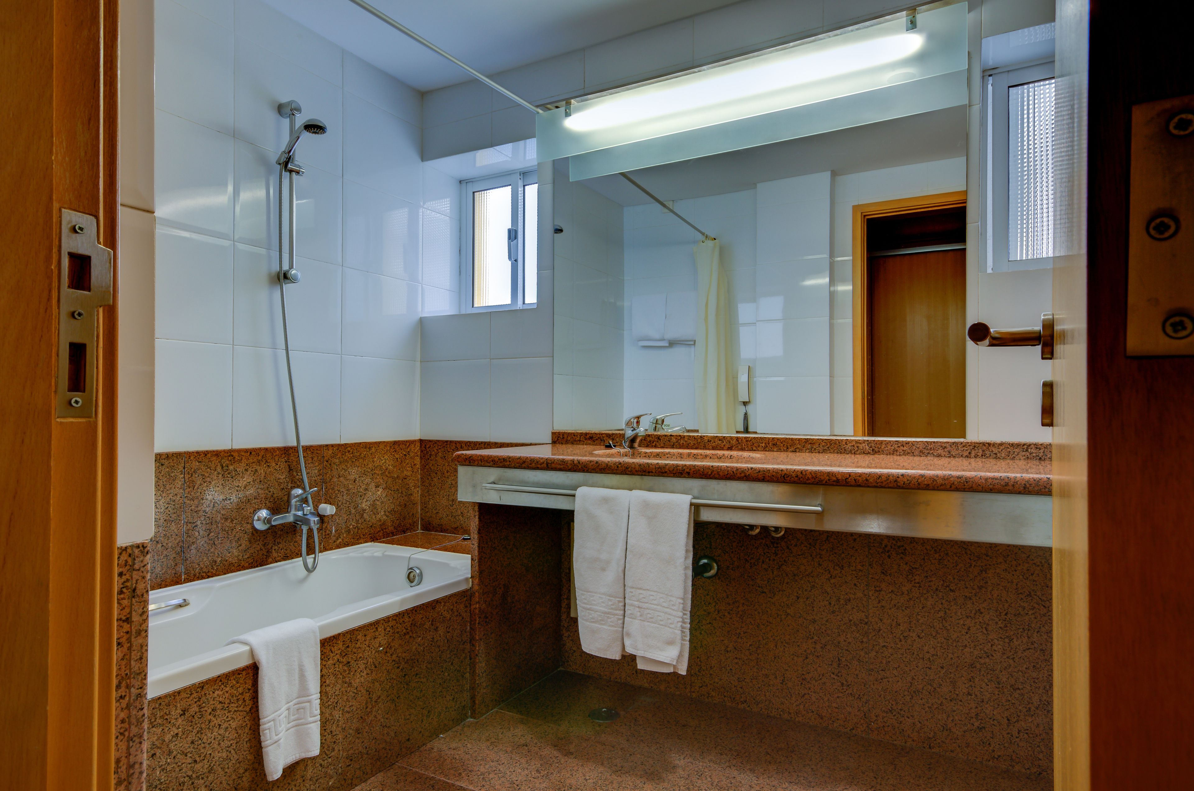 A bathroom with a bathtub, a sink, and a mirror.