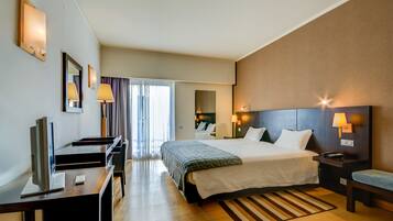 A hotel room with a bed, desk, TV, and a view of the outside.