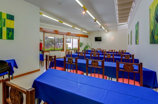 A conference room with blue tables and chairs, large windows, and a flat-screen TV on the wall.