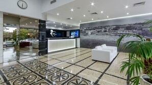 A hotel reception area with a modern design, including a reception desk, seating area, and a large wall mural. - Hotel Alvorada (Cascais)