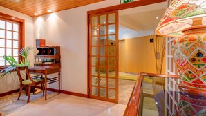 A hotel lobby with a wooden ceiling, a wooden table with chairs, a decorative lamp, and a door leading to another room. - Hotel Alvorada (Cascais)