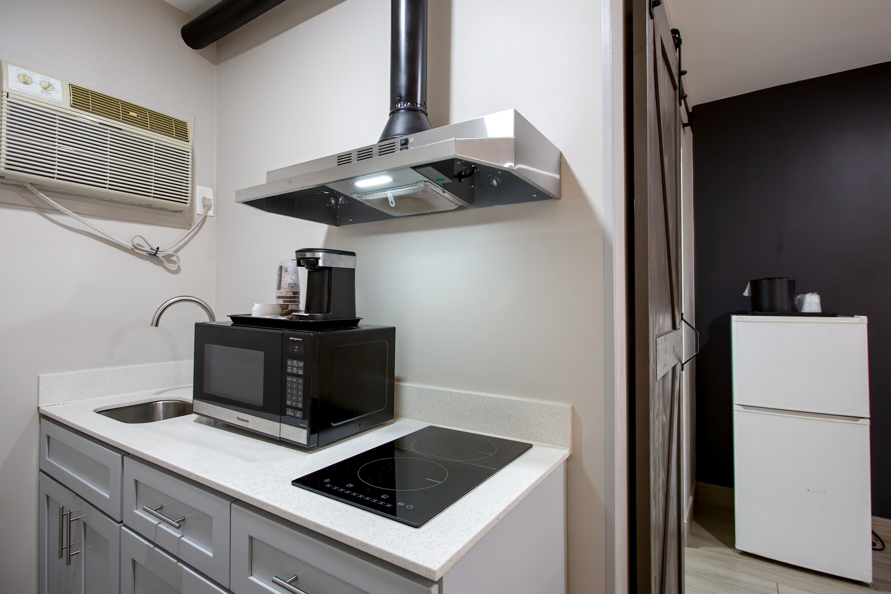 A compact kitchen with a microwave, coffee maker, and induction cooktop.