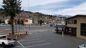 A parking lot with a white pickup truck, a building with a red sign, and a mountain in the background.
