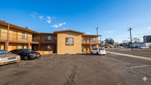 A multi-story motel with a central entrance, parking lot, and a street view.