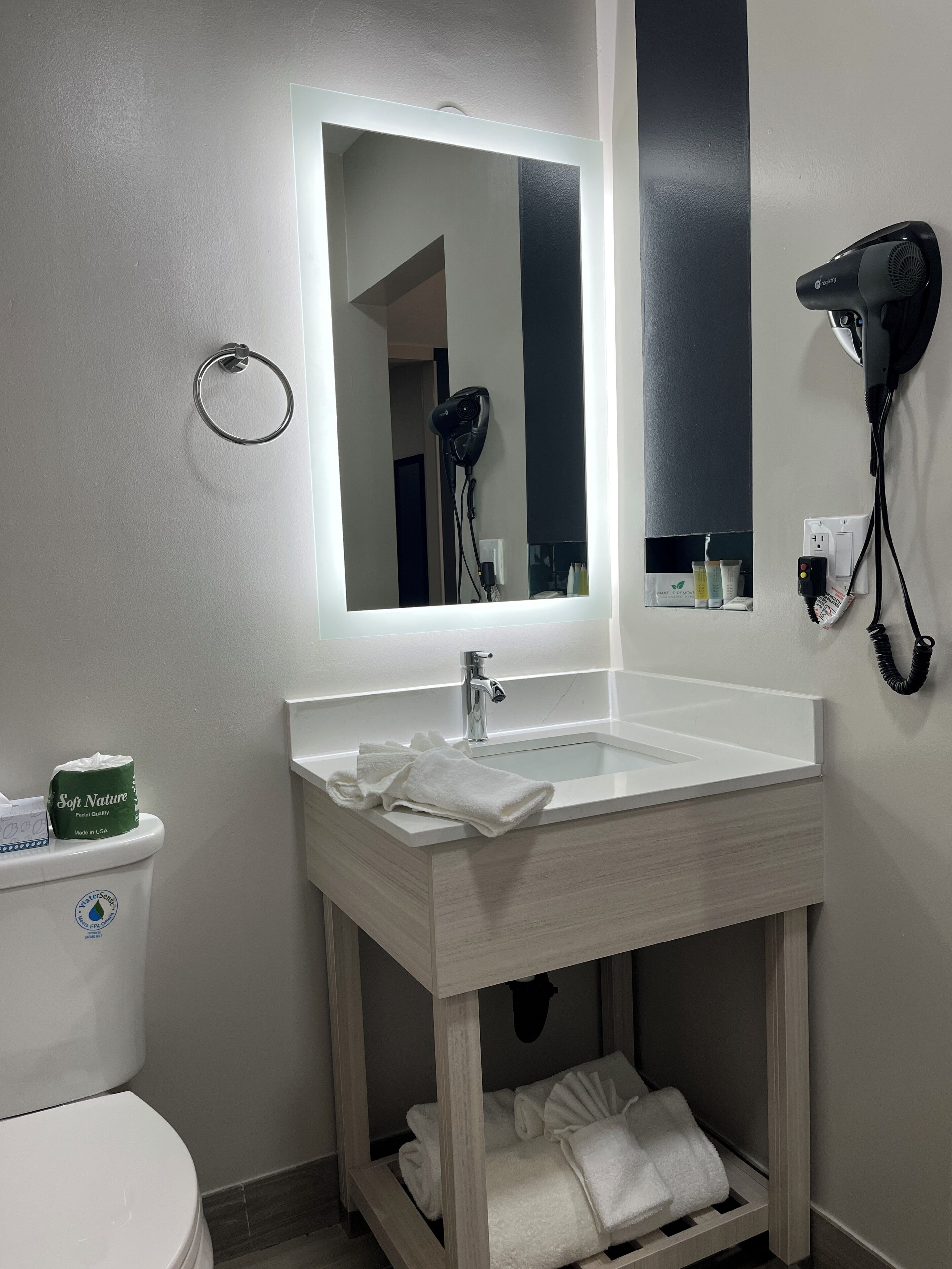 A bathroom with a white sink, mirror, and hair dryer mounted on the wall.