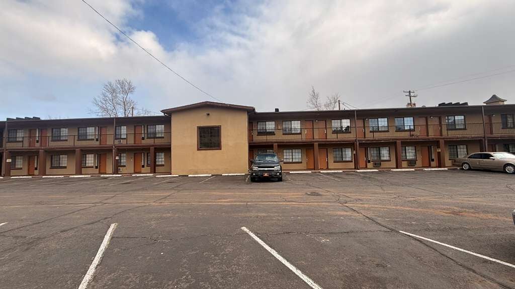 Un motel à plusieurs étages avec un parking situé à l’avant.
