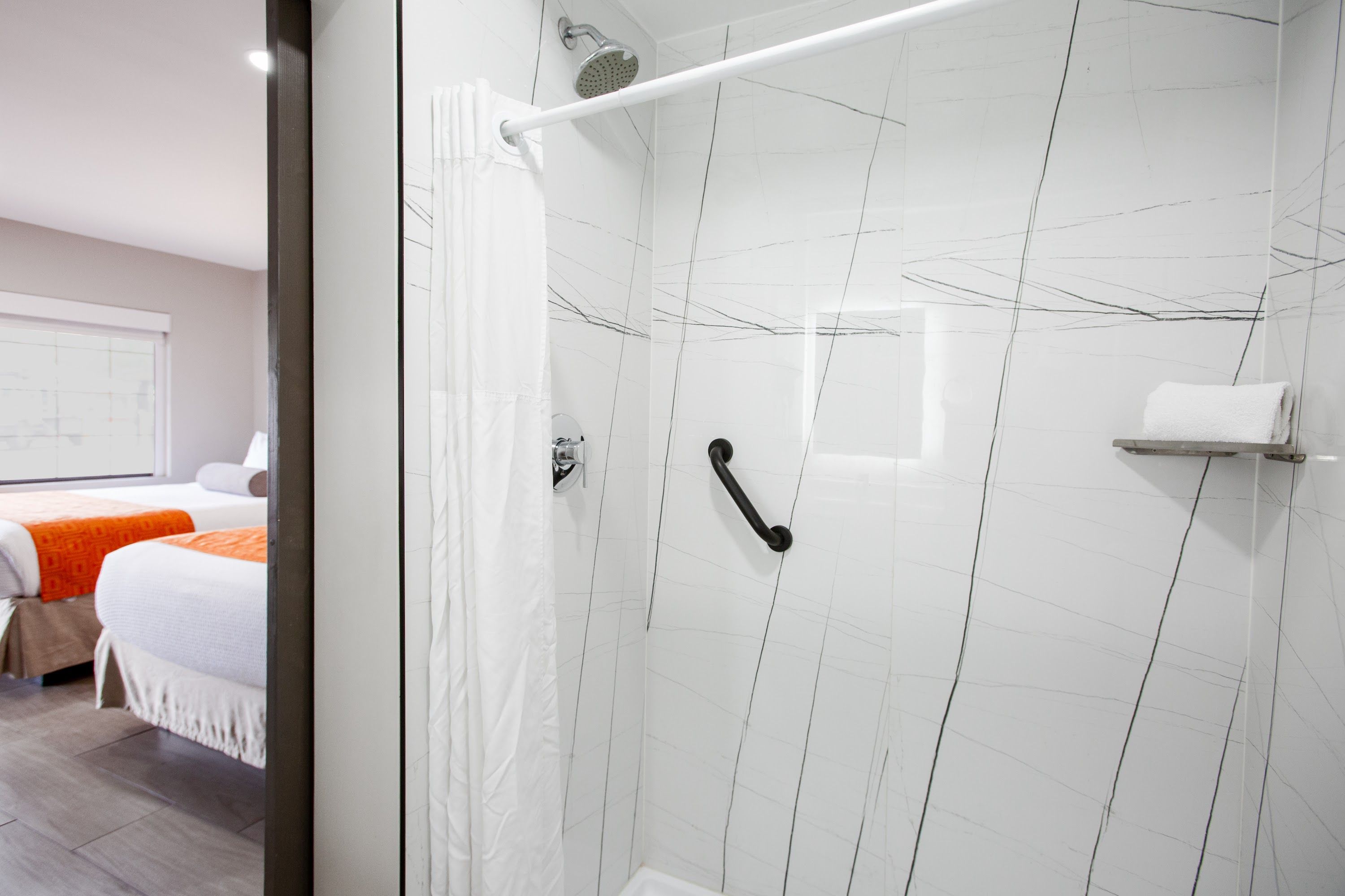 A modern bathroom with a glass shower enclosure, a white towel rack, and a visible showerhead.