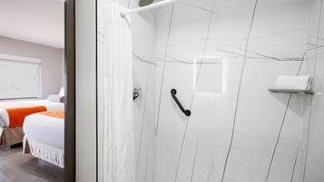 A modern bathroom with a glass shower enclosure, a white towel rack, and a visible showerhead.