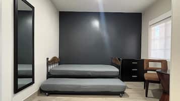 A compact room with a bed, a chair, a desk, and a window.