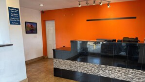 A reception area with a check-in counter, a sign detailing breakfast hours and pet policy, and a door leading to another room.