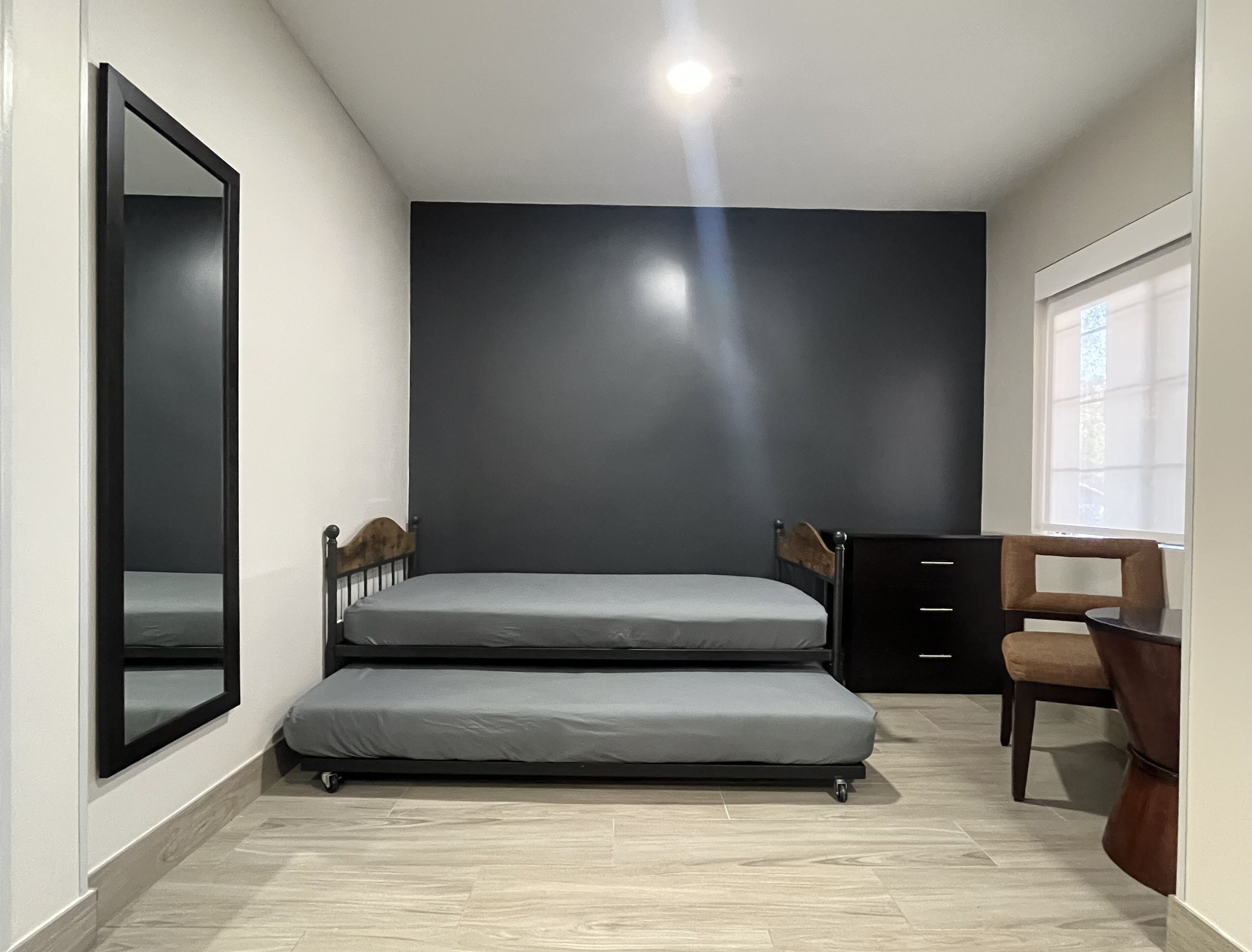 A compact room with a bed, a chair, a desk, and a window.