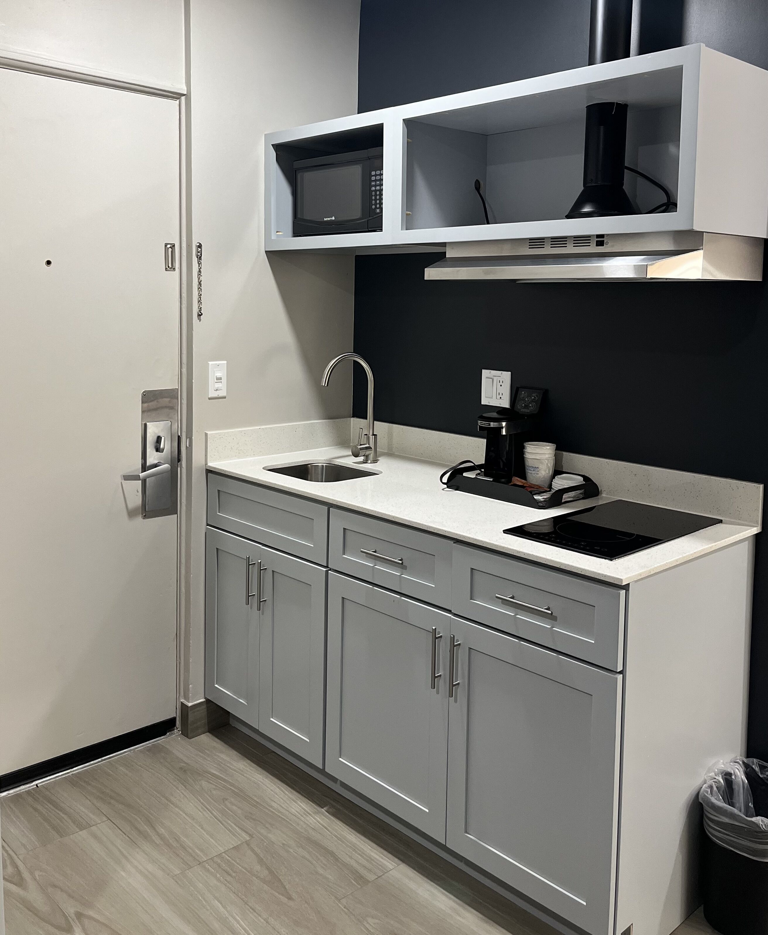 A compact kitchen with a sink, a coffee maker, and a microwave.