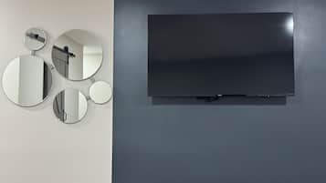 A wall-mounted TV and three circular mirrors on a dark wall.