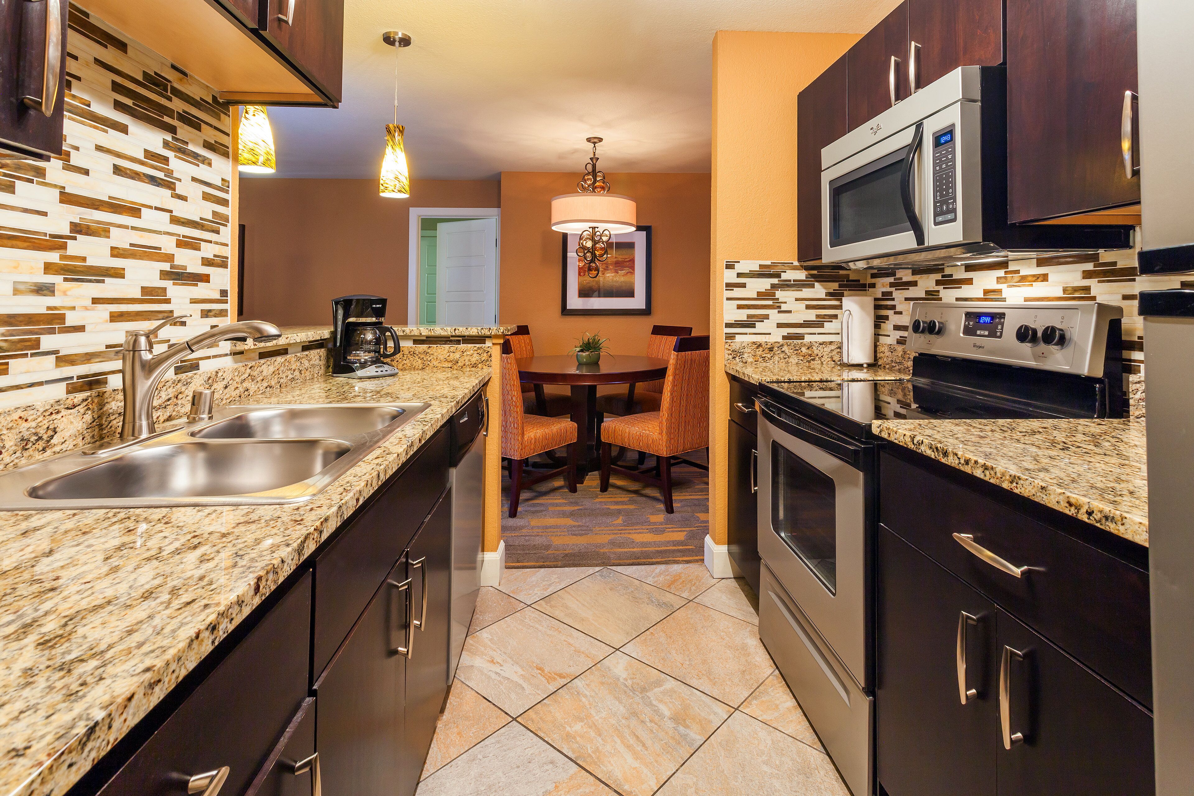 A modern kitchen with granite countertops, stainless steel appliances, and a dining area with a table and chairs.