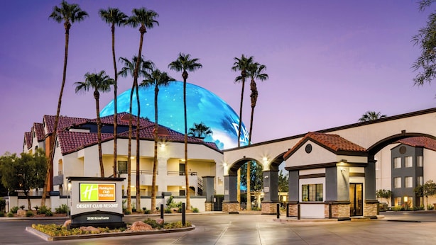 Un Holiday Inn con una gran estructura en forma de cúpula, palmeras y un cartel que indica que es un Desert Club Resort.