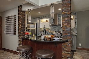 A modern kitchen with a central island, bar stools, a refrigerator, and a stone accent wall. - Holiday Inn Club Vacations at Desert Club Resort by IHG (Las Vegas)