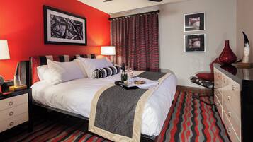 A hotel room with a bed, a nightstand, a dresser, a ceiling fan, and a red carpet.