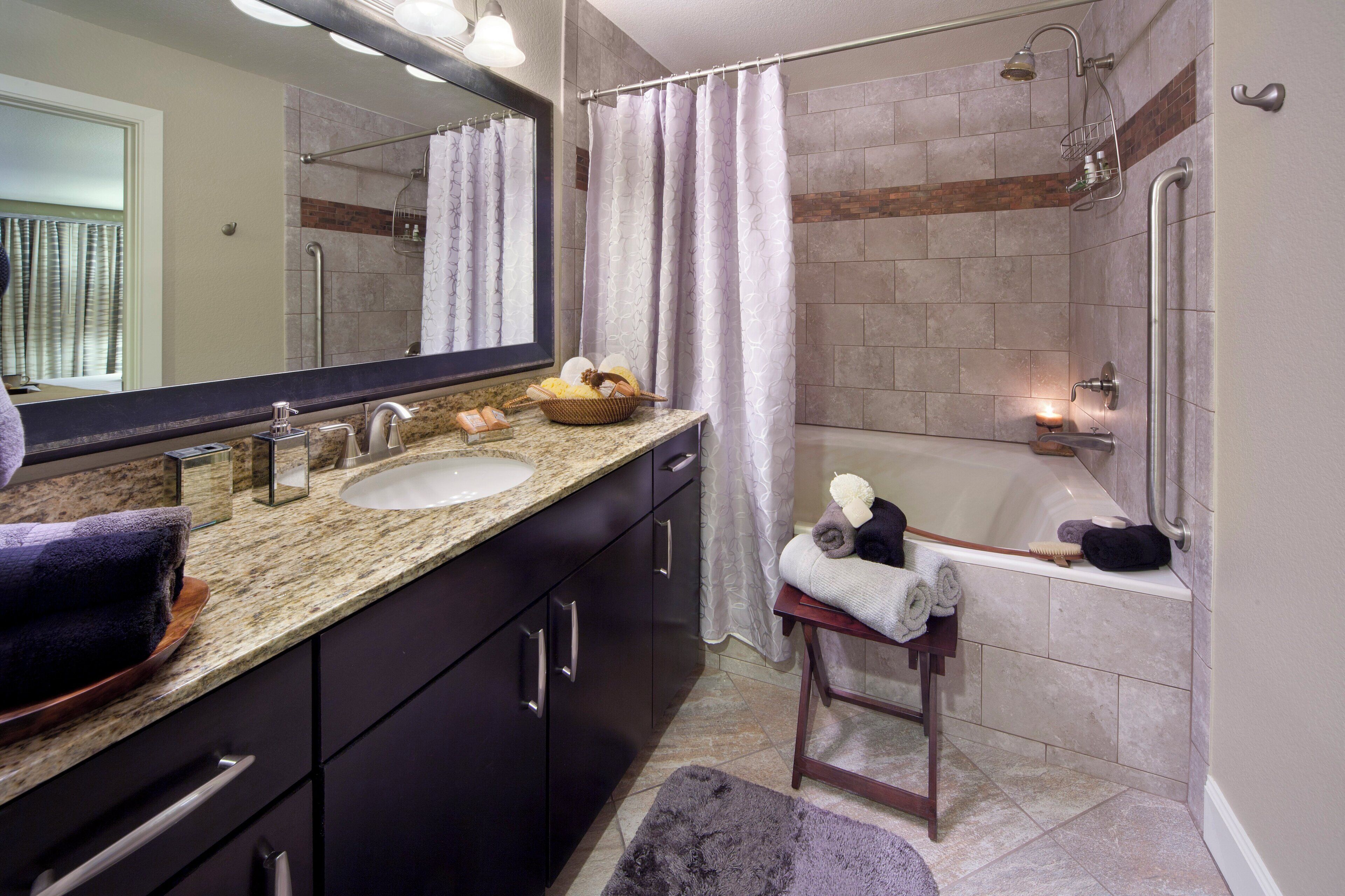 A bathroom with a bathtub, a shower, a vanity with a sink, and a mirror.