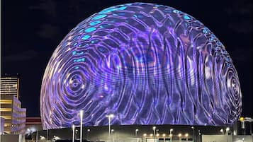 A large spherical building with a textured surface and a series of lights at its base.