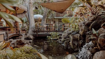 An indoor garden with a water feature, seating area, and tropical plants.