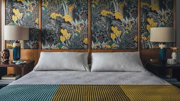 Una camera d'albergo con un letto grande, due comodini, una parete decorata con un arazzo floreale e una lampada su ogni comodino.