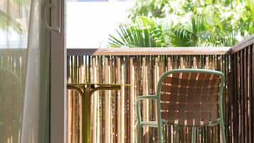 A bamboo fence, a green chair, and a table with a metal frame.