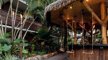 A tropical resort with a bamboo structure, hanging swings, and lush vegetation.