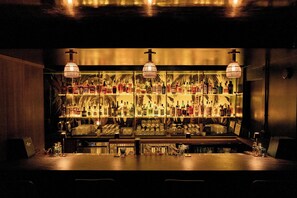 A bar area with shelves of bottles and glasses, a bar counter, and hanging lamps. - White Sands Hotel (Honolulu)