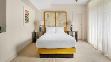 Une chambre d’hôtel avec un grand lit, deux tables de chevet, un ventilateur de plafond et une fenêtre avec des rideaux.