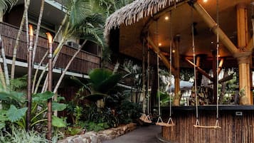 A tropical resort with a bamboo structure, hanging swings, and lush vegetation.