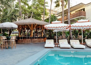 A poolside area with lounge chairs, umbrellas, and a bar. - White Sands Hotel (Honolulu)