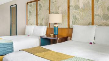 A hotel room with two beds, a nightstand, a lamp, and a mirror.