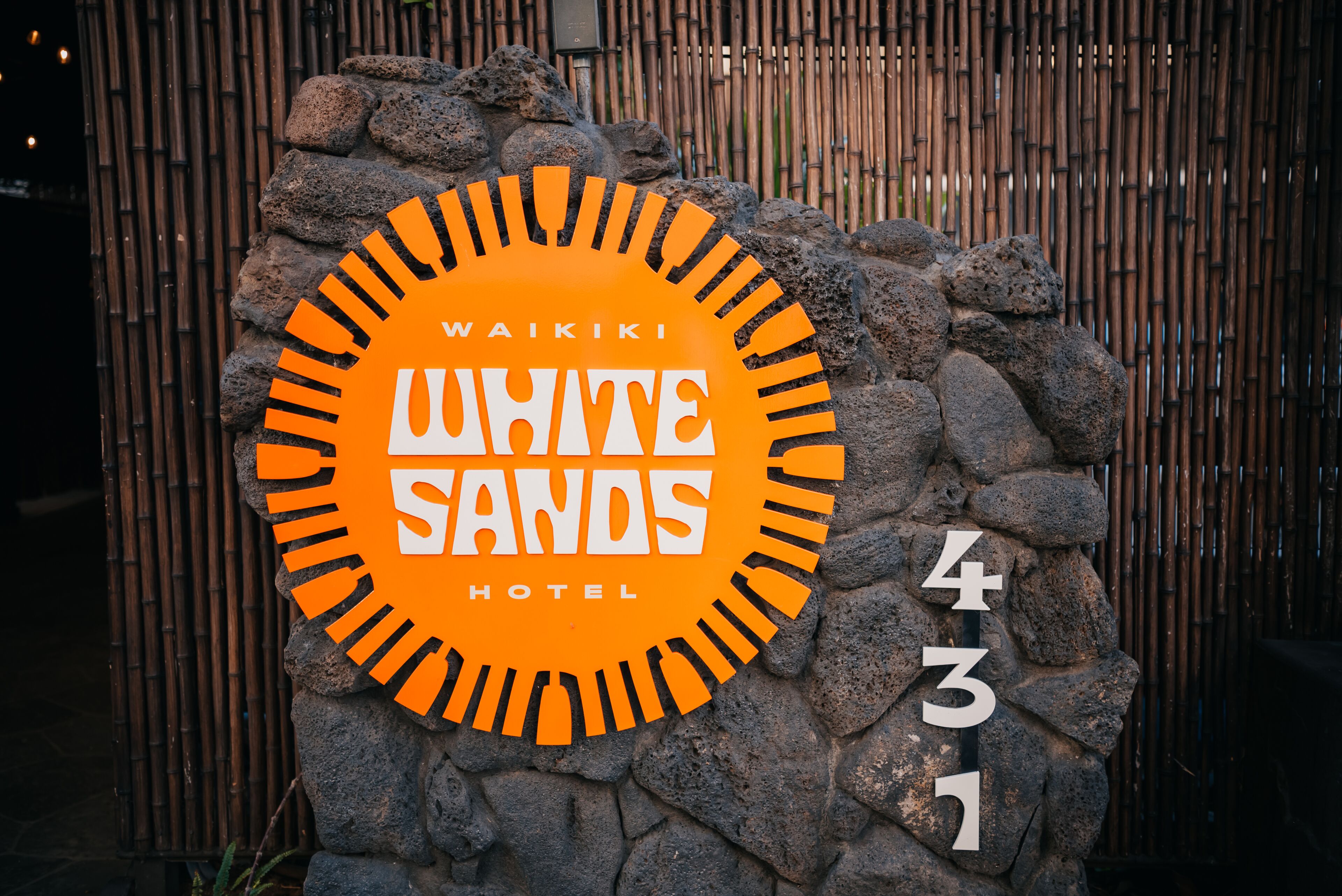 A sign for Waikiki White Sands Hotel, featuring a circular design with the hotel's name and address.