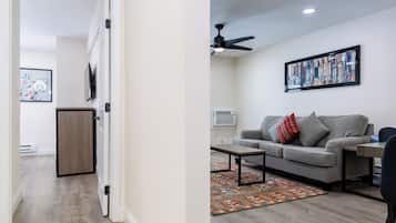 A living room with a grey sofa, a coffee table, and a ceiling fan.