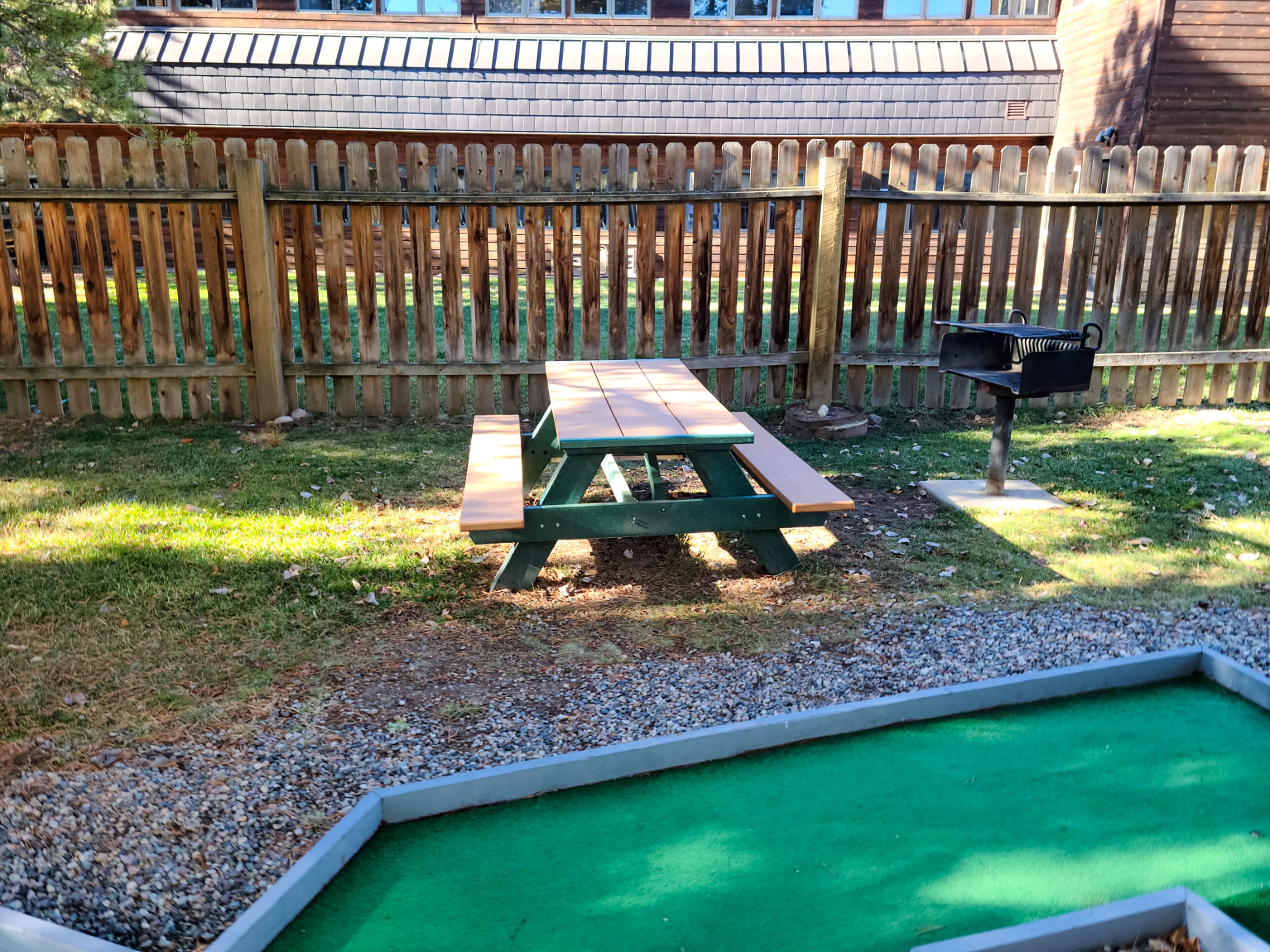 A picnic table in a backyard with a wooden fence and a small pool.