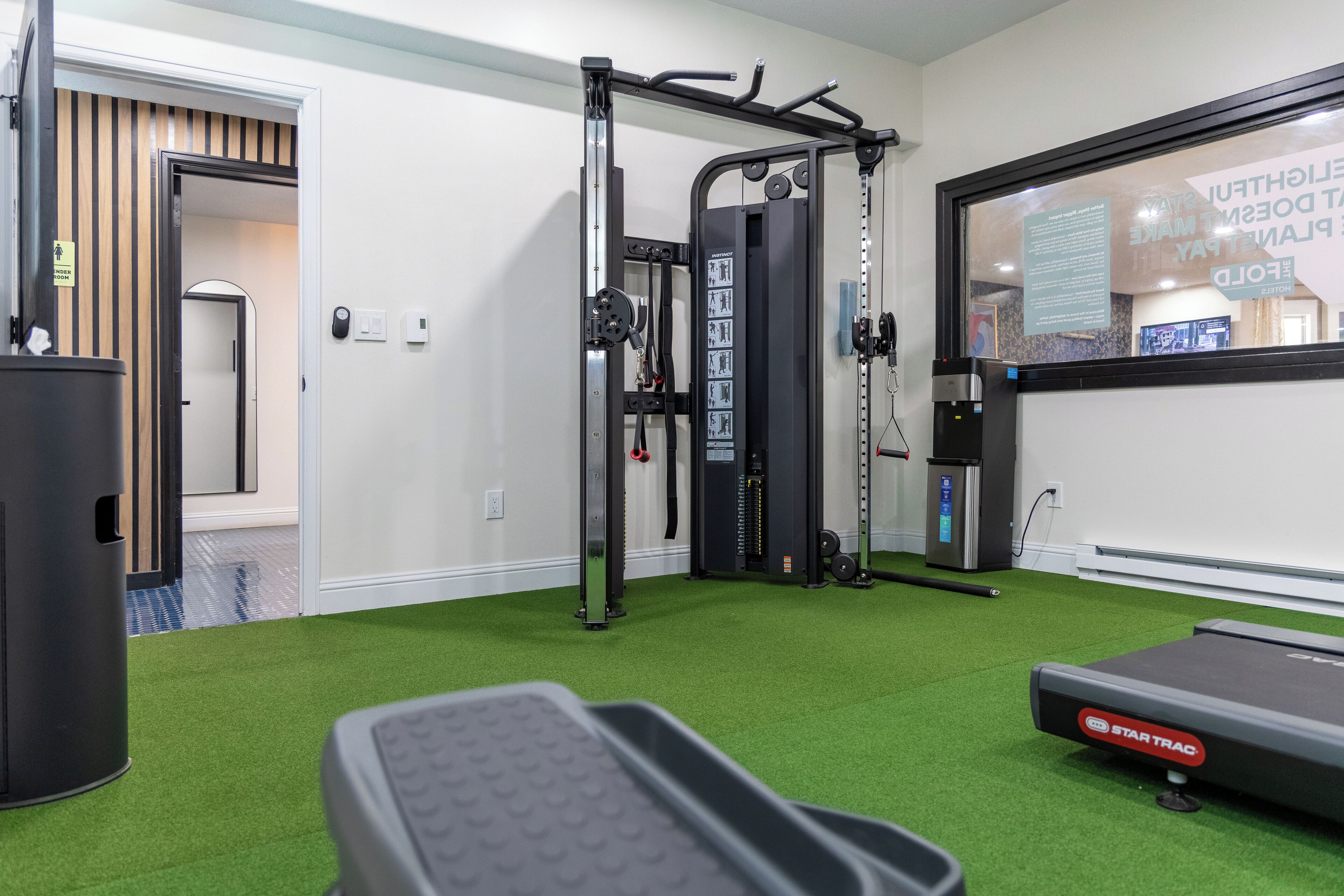 A gym with a pull-up bar, weight machine, and a treadmill.