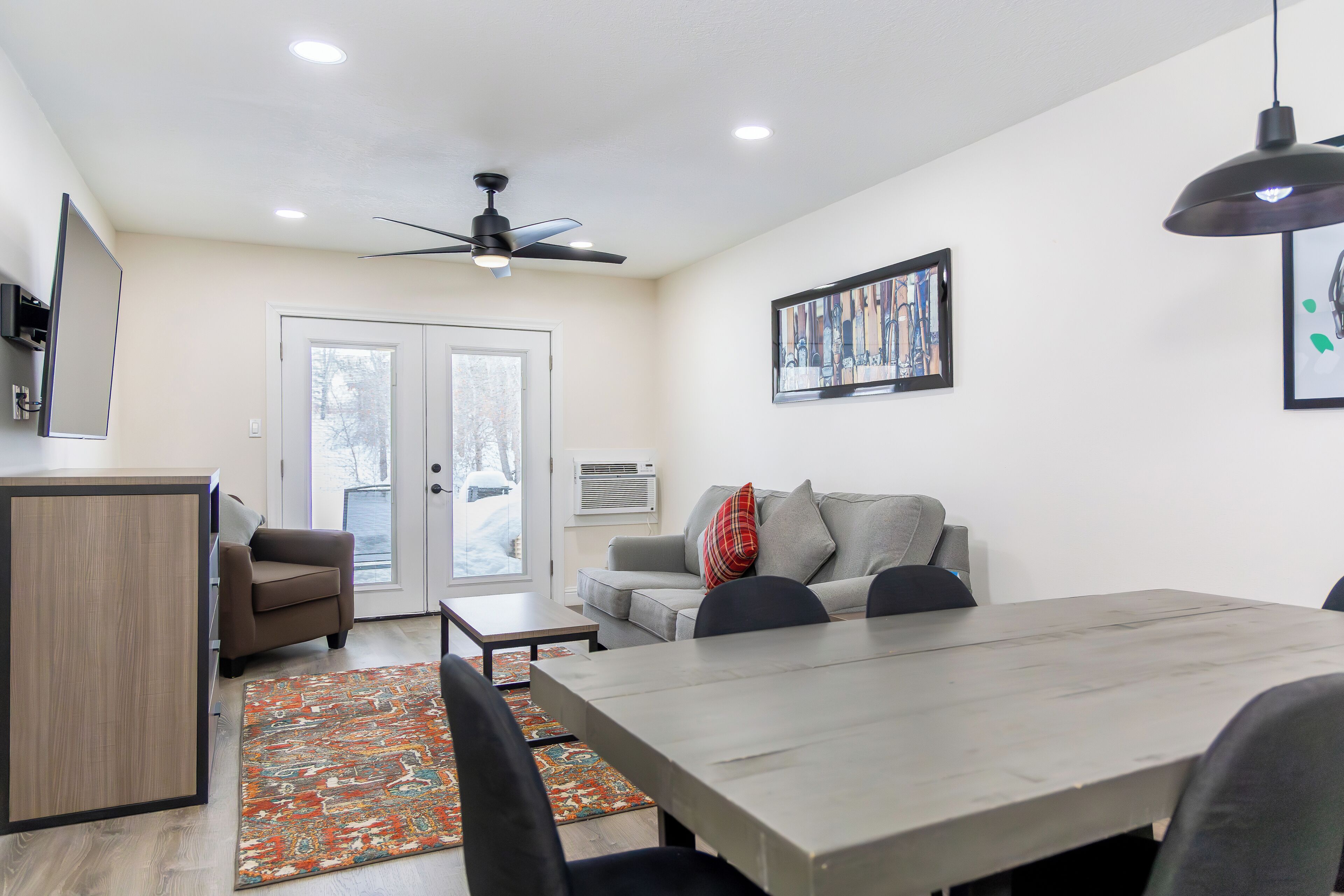 Una sala de estar moderna con una mesa de comedor, sofá y ventilador de techo.