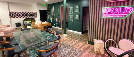 A modern hotel lobby with a glass table, comfortable seating, a neon sign, and ski-themed decor.