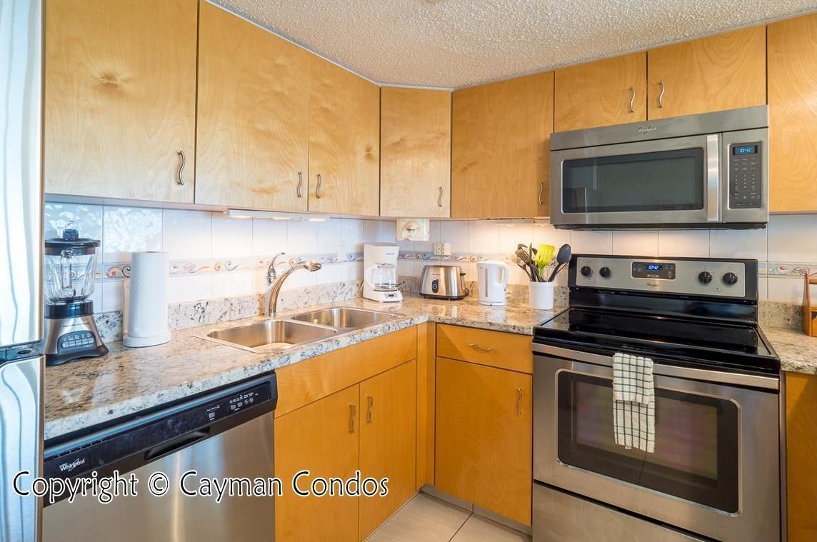 A kitchen with wooden cabinets, stainless steel appliances, a dishwasher, and a microwave.
