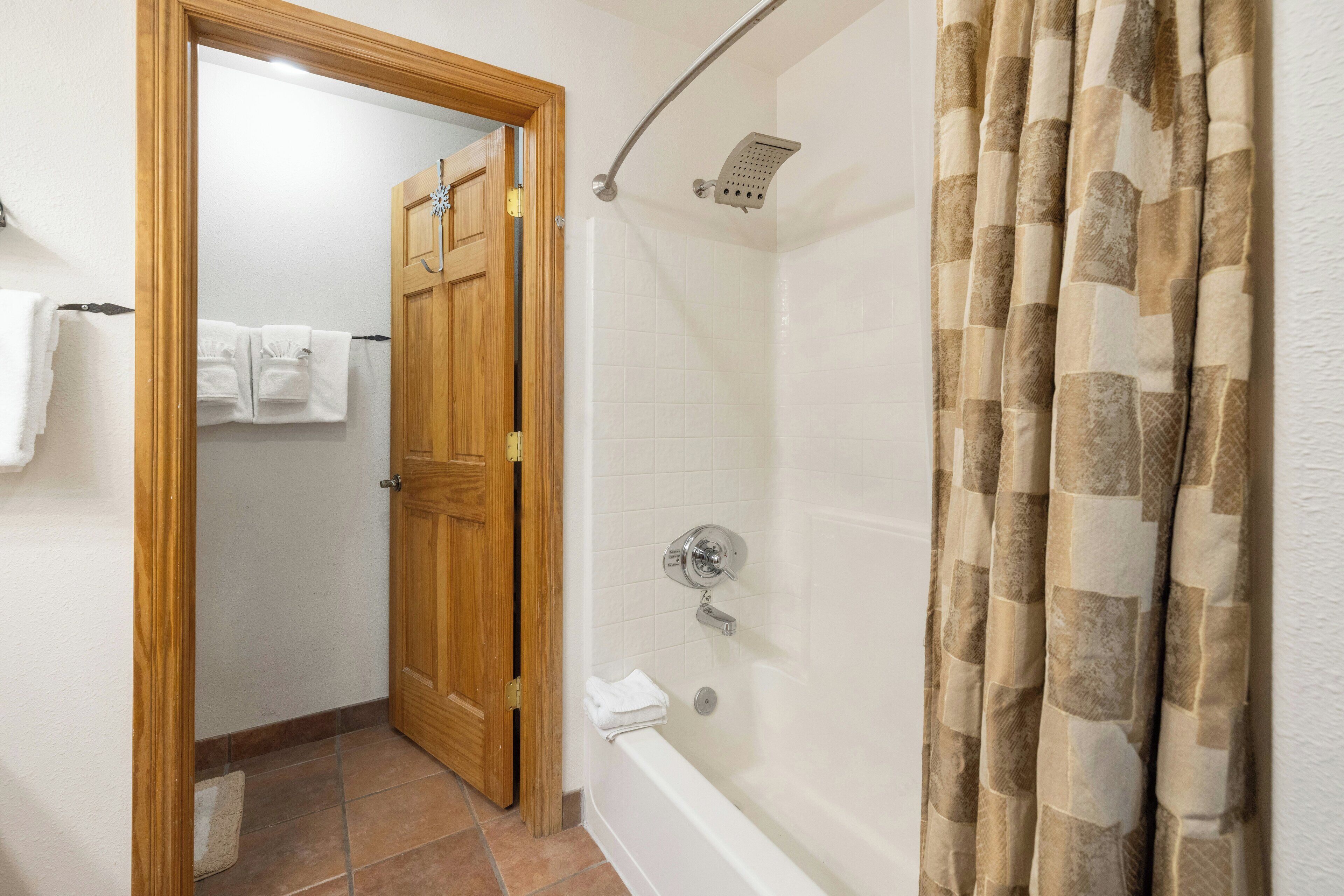 A bathroom with a shower, a wooden door, and a towel rack.