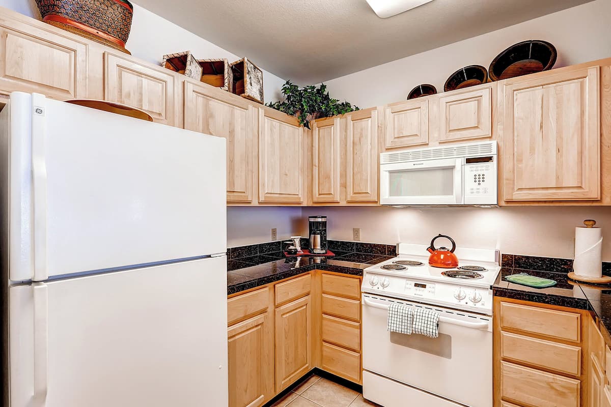 A kitchen with wooden cabinets, a white refrigerator, a stove, and a microwave.