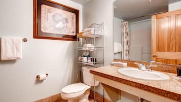 Et badeværelse med toilet, vask og hylder med toiletartikler.