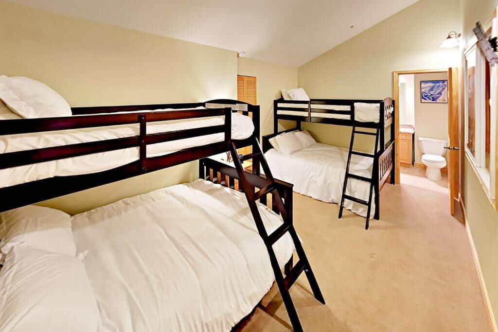 Ein Zimmer mit Etagenbetten, einem Badezimmer mit Toilette und Waschbecken sowie einer Tür zu einem weiteren Raum.