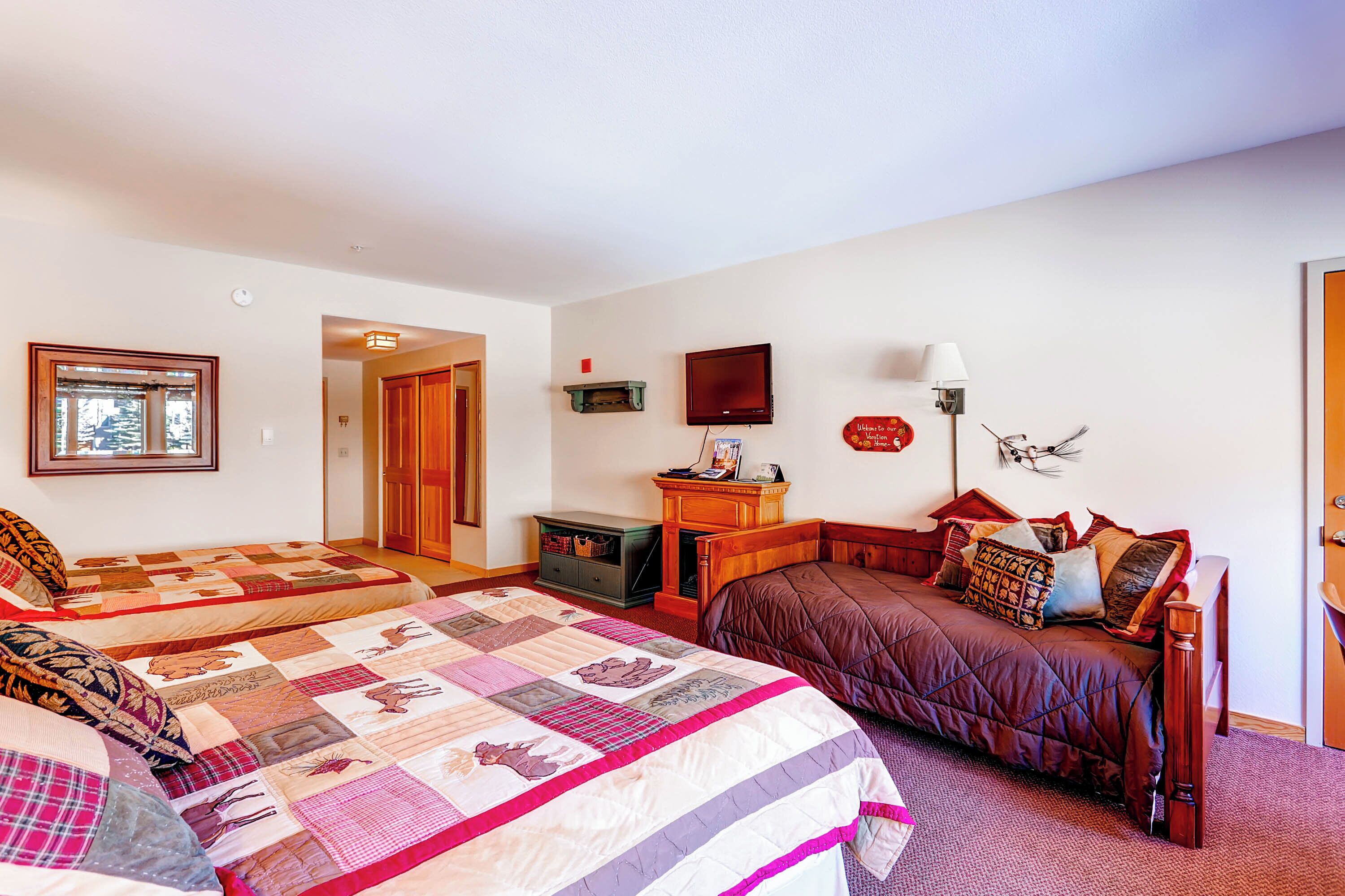 A bedroom with two beds, a dresser, a television, and a lamp.