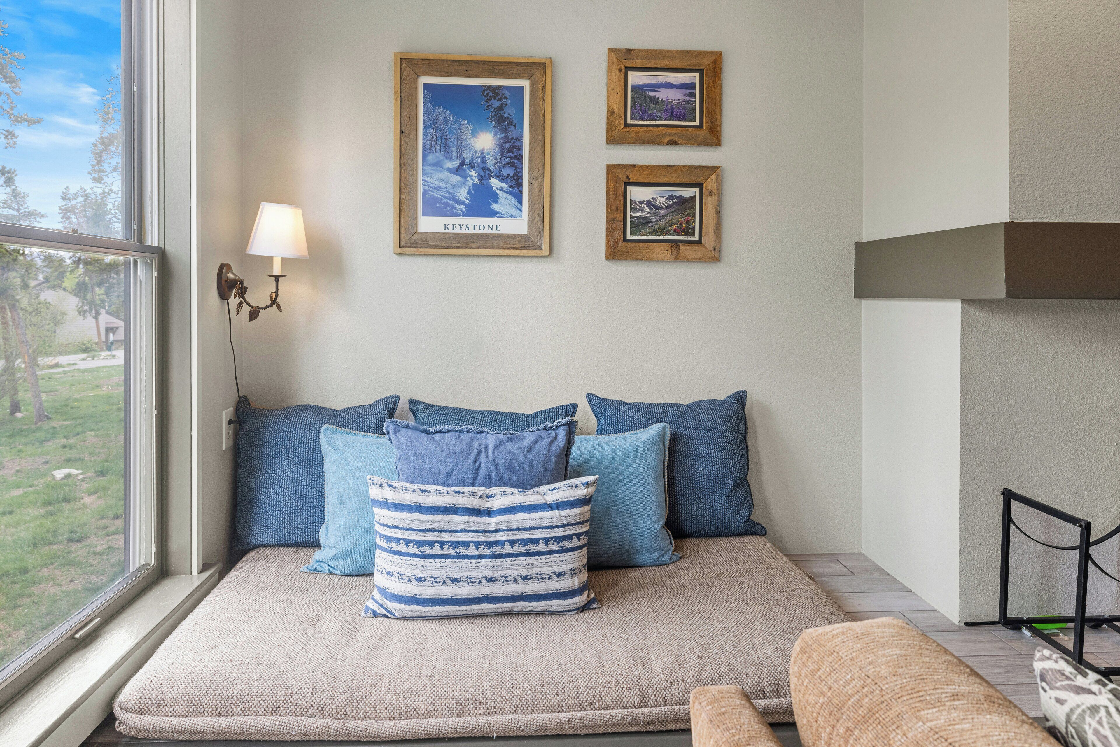 A cozy room with a window seat, framed pictures on the wall, and a lamp.