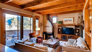 A cozy living room with a fireplace, wooden ceiling, and a large TV. - Aspen Ridge Condominiums by Vail Resorts (Keystone)