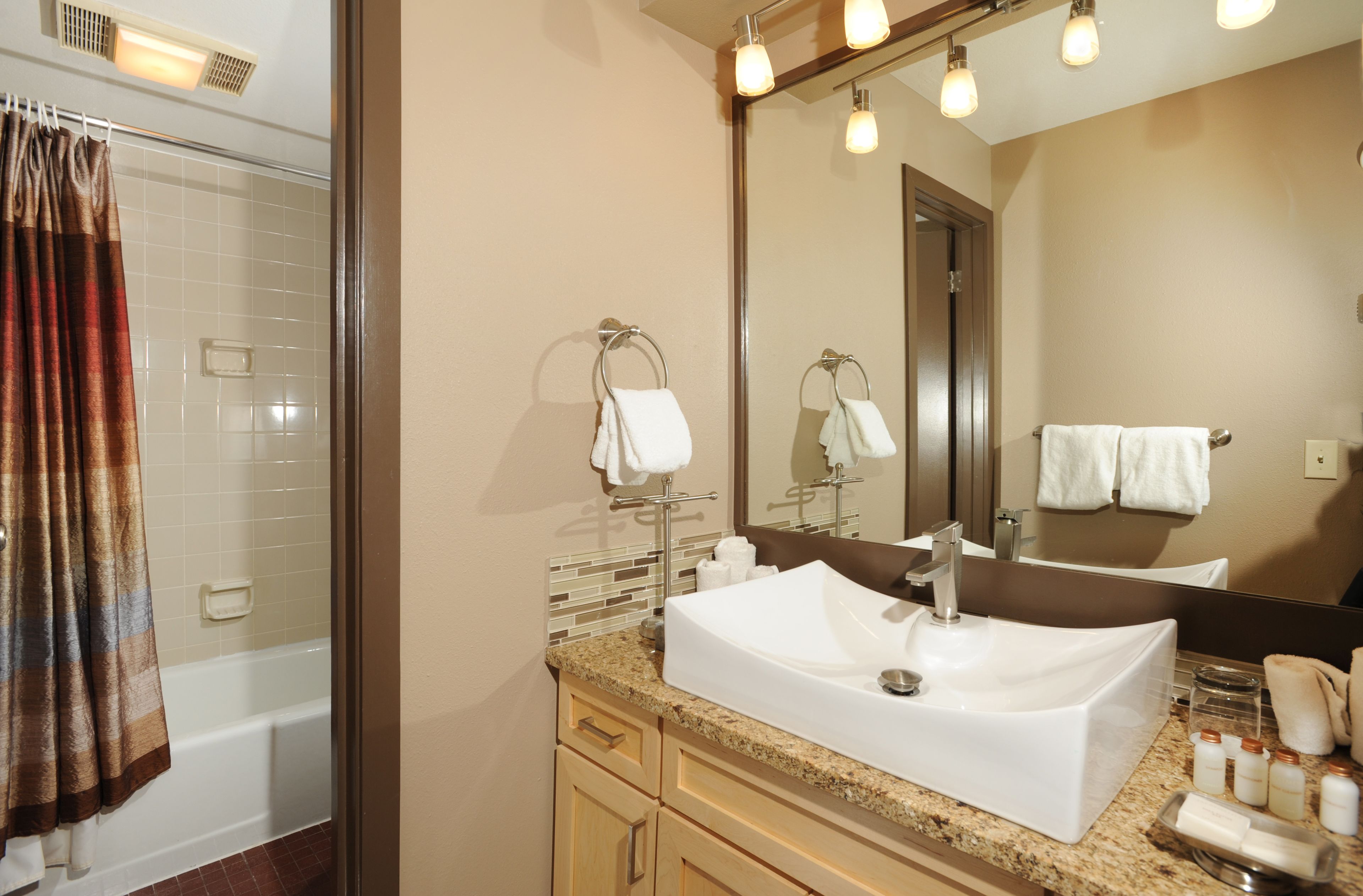 Une salle de bain avec une baignoire, un lavabo, un miroir et un rideau de douche.