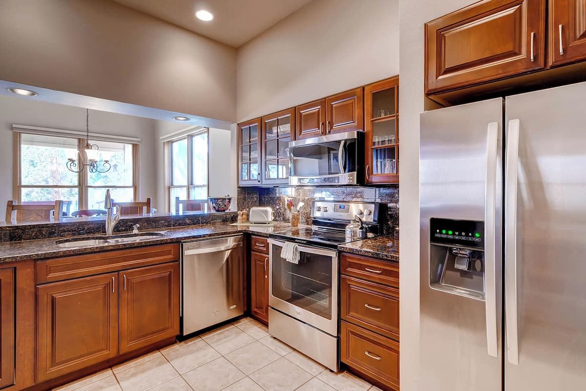 A modern kitchen with wooden cabinets, stainless steel appliances, a built-in microwave, and a water dispenser.