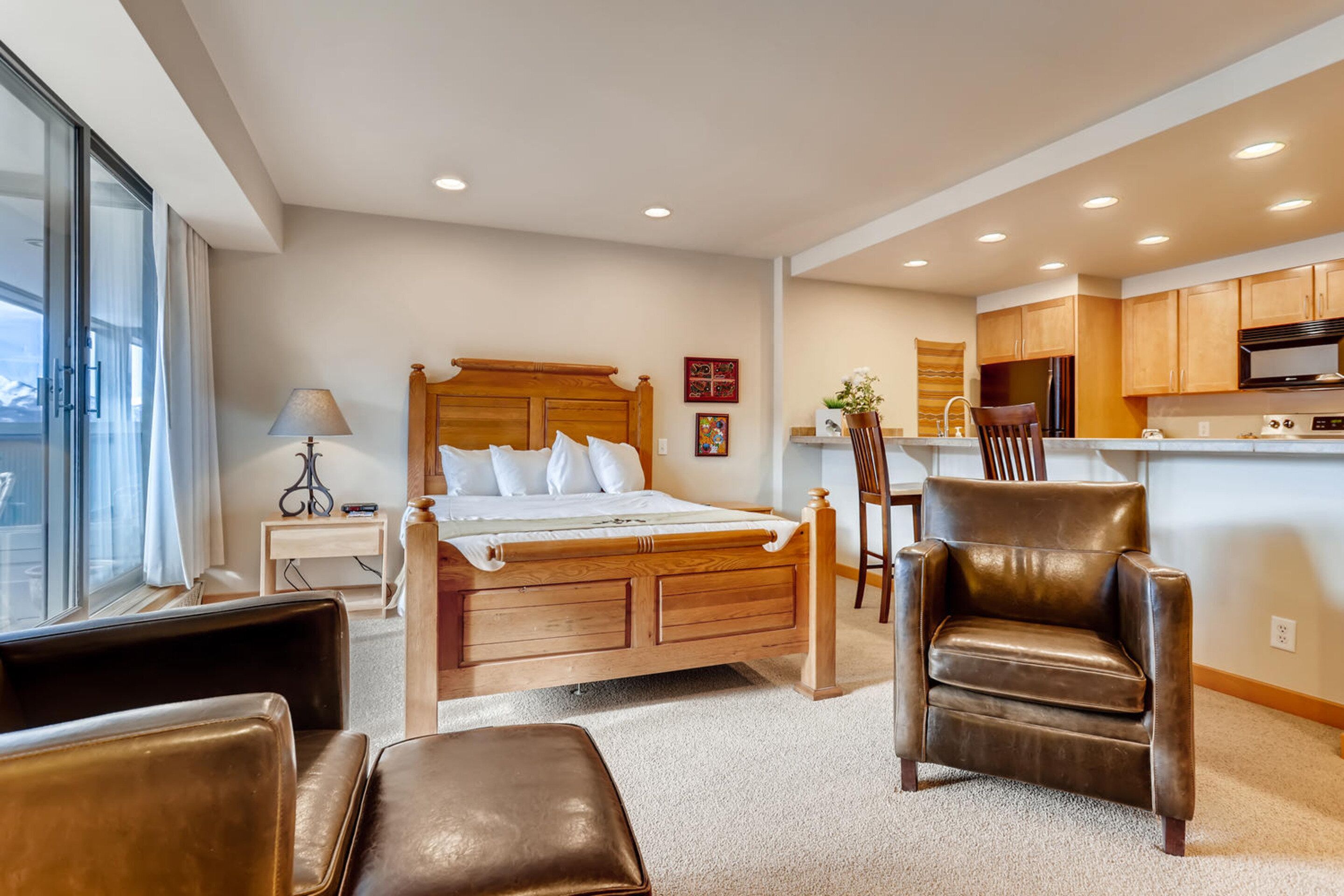 A bedroom with a wooden bed, a nightstand, a chair, and a desk.