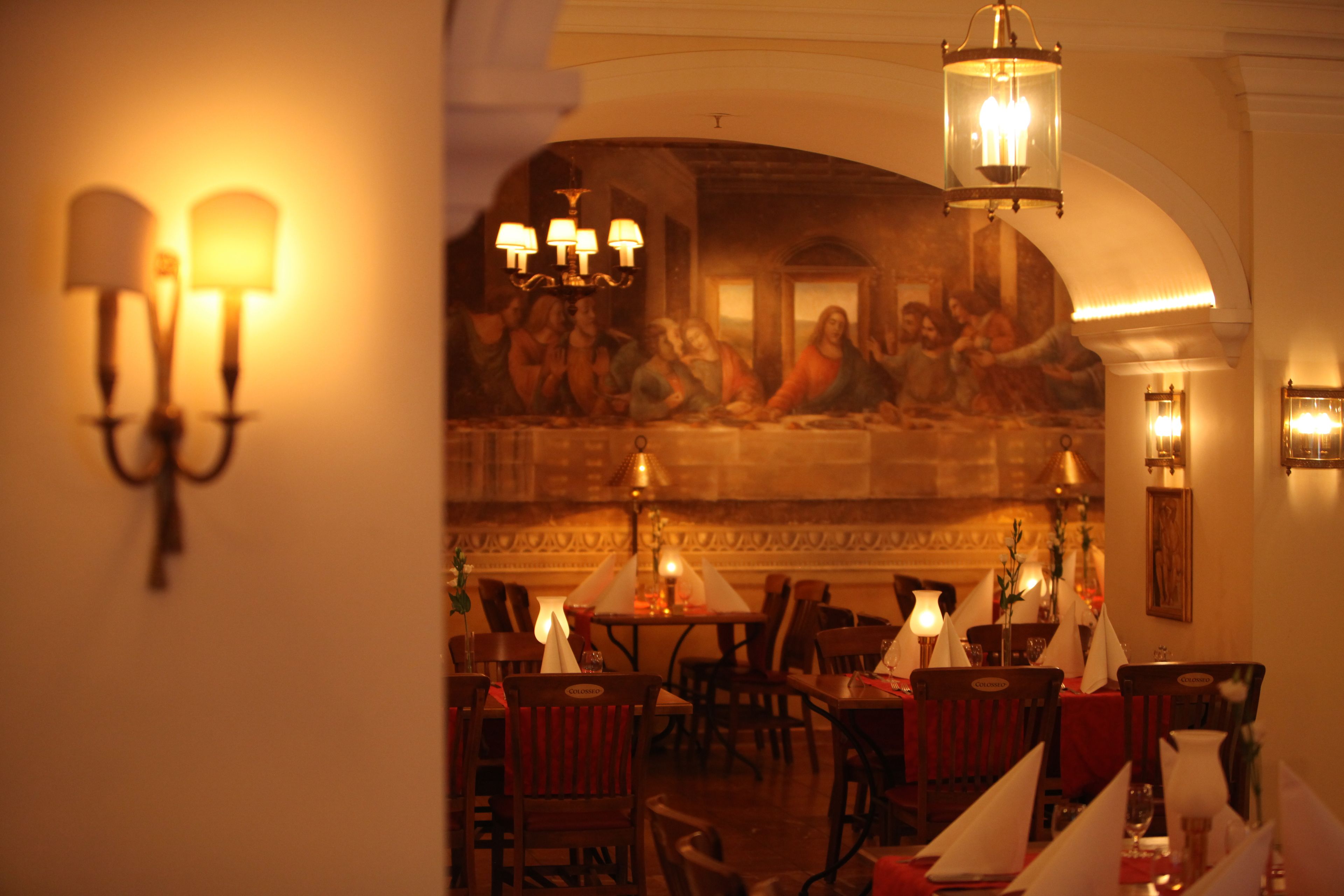 Ein Restaurant mit gedeckten Tischen, einer Wandmalerei und Kristallleuchtern.